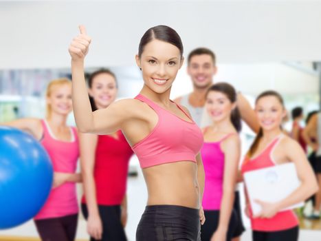 fitness, sport, training and lifestyle concept - personal trainer with group of smiling people in gym