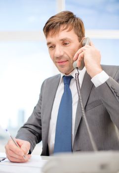 technology, business, communication and office concept - handsome businessman working with phone and documents