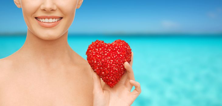 health, beauty and charity concept - beautiful woman with red heart