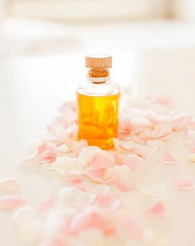 spa, health and beauty concept - closeup of essential oil and rose petals