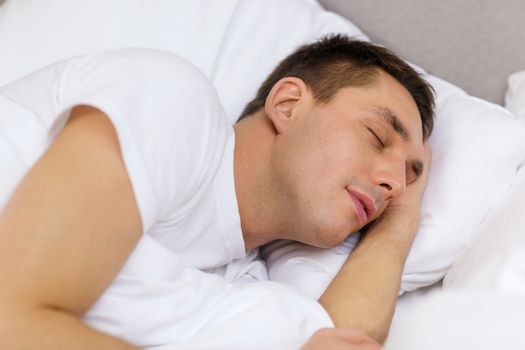 hotel, travel and happiness concept - handsome man sleeping in bed