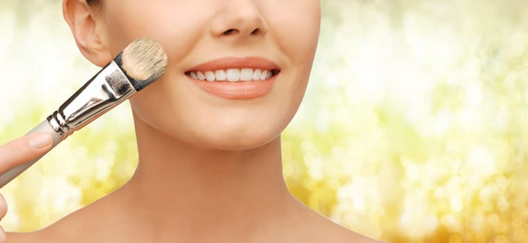 beauty amd make-up concept - closeup picture of beautiful woman with brush applying cream foundation