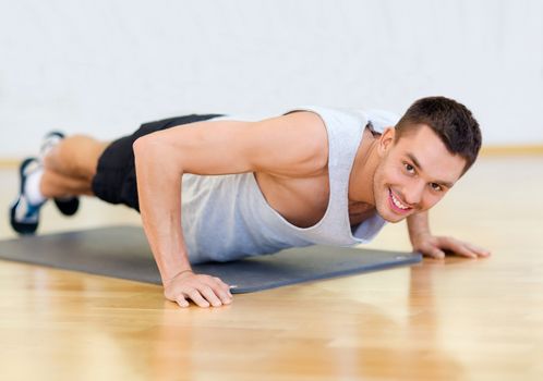 fitness, sport, training, gym and lifestyle concept - smiling man doing push-ups in the gym or at home