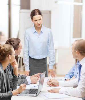 business, technology and office concept - strict female boss talking to business team