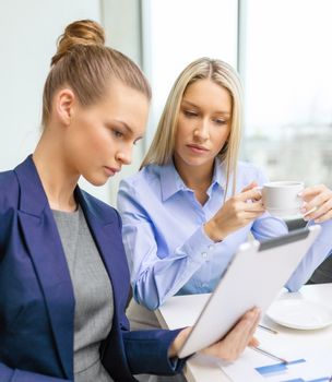 business, technology and office concept - serious businesswomen with tablet pc computers having discussion in office