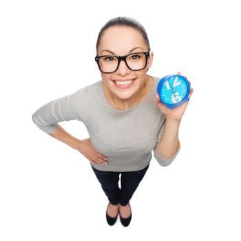 time and deadline concept - smiling woman in eyeglasses with blue clock