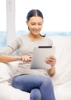 home, technology and internet concept - woman sitting on the couch with tablet pc at home