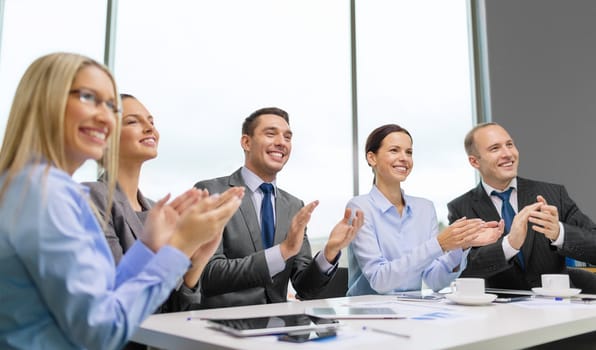 business, technology and office concept - happy business team with laptop computers, documents and coffee clapping hand