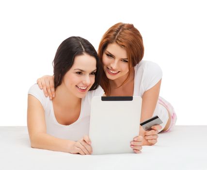 online shopping and technology concept - two smiling teenage girls with tablet pc computer and credit card