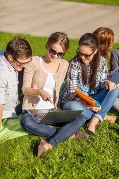 summer, internet, education, technlogy and campus concept - group of students or teenagers with laptop, notebooks, files and folders