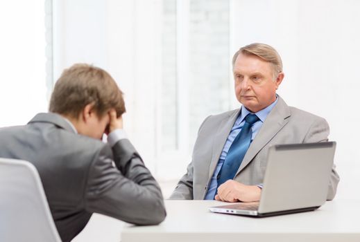 business, technology and office concept - older man and young man having argument in office