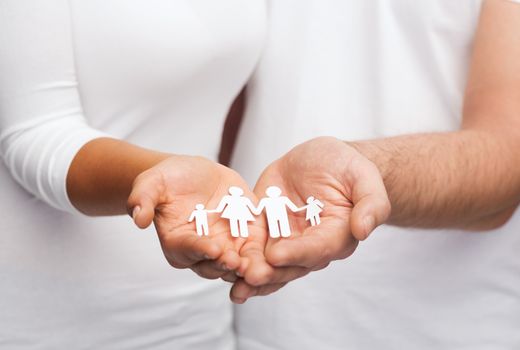 love and relationships concept - closeup of couple cupped hands showing paper man family