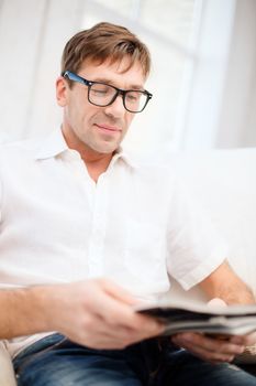 leisure, education and lifestyle concept - man with magazine at home