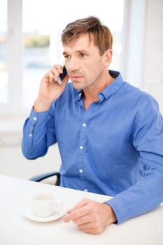 business, communication, modern technology concept - buisnessman with cell phone and cup of coffee