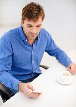 business, communication, modern technology concept - buisnessman with smartphone and cup of coffee