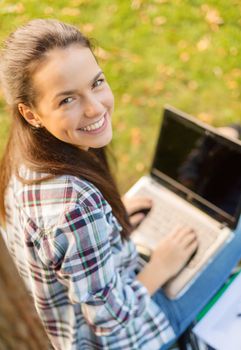 education, technology and internet concept - smiling teenager with laptop computer