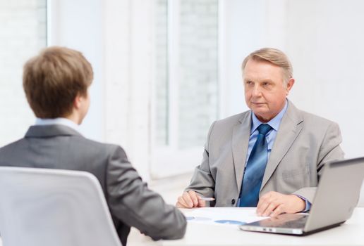 business, technology and office concept - older man and young man having meeting in office