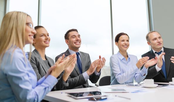 business, technology and office concept - happy business team with laptop computers, documents and coffee clapping hand