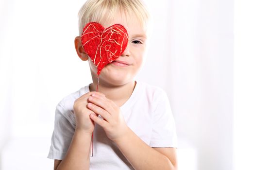 Little caucasian boy shows a red Valentine heart