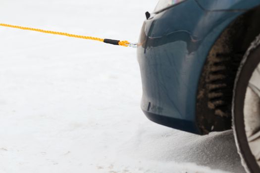 transportation, winter and vehicle concept - closeup of towed car with towing rope