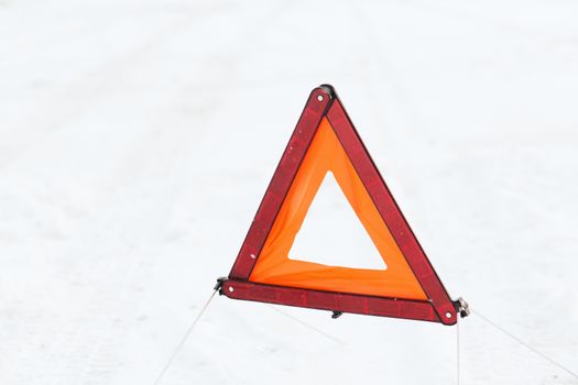 transportation and winter concept - closeup of warning triangle on snow