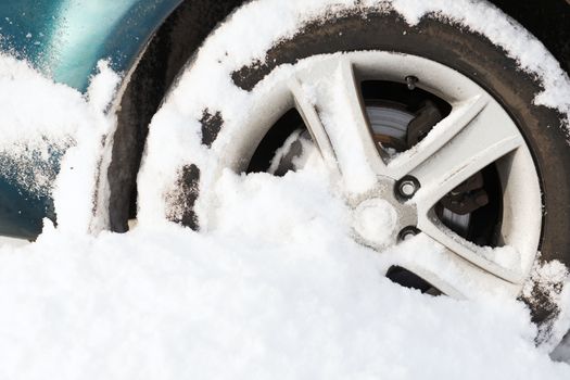transportation, winter and vehicle concept - closeup of car wheel stuck in snow