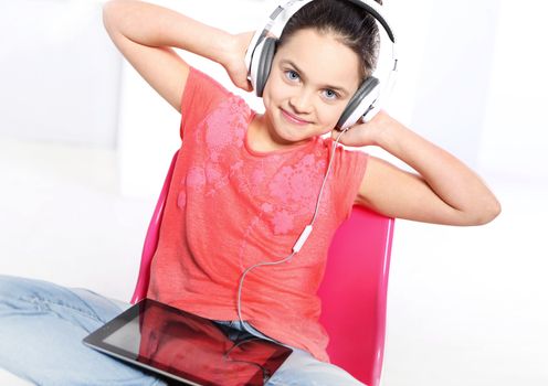 Young girl in a pink shirt with earphones and a tablet