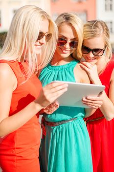 holidays and tourism concept - beautiful blonde girls toursits looking into tablet pc in the city