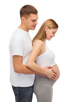 pregnancy, parenthood and happiness concept - happy young family expecting child looking at belly