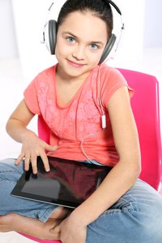 Young girl in a pink shirt with earphones and a tablet