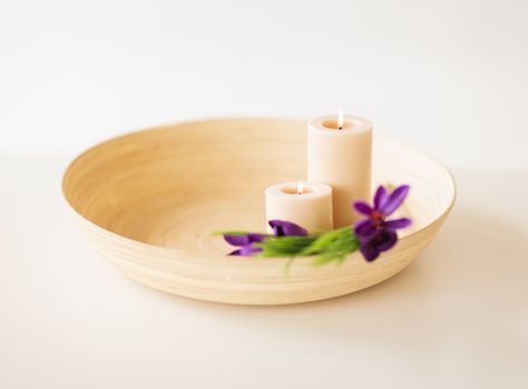 spa, health and beauty concept - candles and iris flowers in wooden bowl