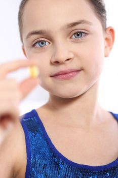 Caucasian girl holding a yellow pill