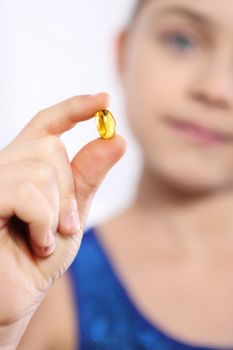 Caucasian girl holding a yellow pill