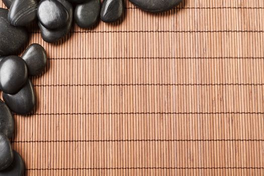 spa, heath and beauty concept - massage stones on bamboo mat