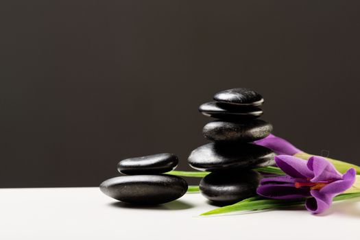 spa, heath and beauty concept - massage stones with flowers on mat