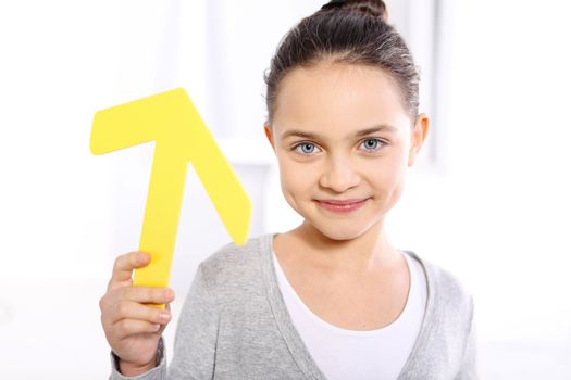 Caucasian girl holding a symbol of the yellow arrow pointing up