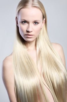 Beautiful long-haired woman in a natural makeup nude on a light background