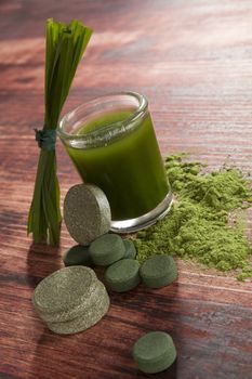 Chlorella, spirulina and wheatgrass on brown wooden background. Alternative medicine, detox.