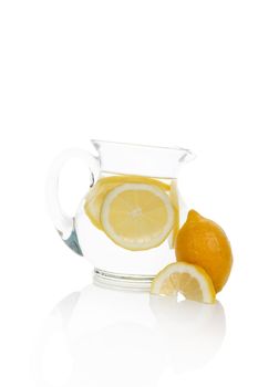 Water with lemon slices in glass jar isolated on white background with reflection. Delicious fresh water drinking.