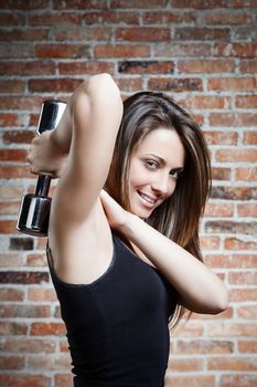Portrait of Young smiling fit woman lifting dumbbells