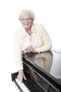 elderly lady in yellow at the piano in studio with white background