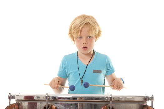 young boy playing kettle drum against white background in studio