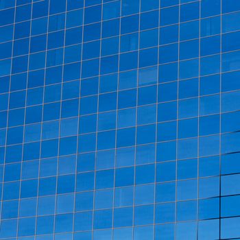 Glass building windows reflection on blue sky