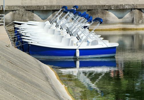 White and blue pedalos parked on the lakeside