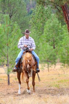 Young cowboy riding his horse in the field 