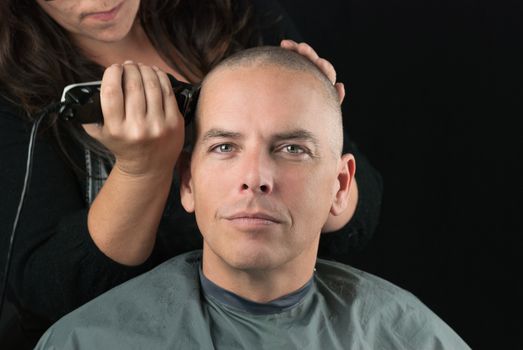 Close-up of a hair stylist using clippers to shave her Clients head.