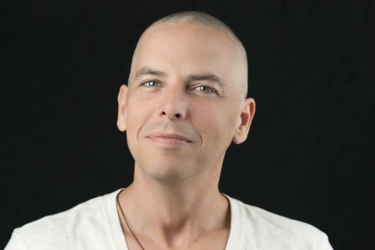 Close-up of a man with a newly shaved head looking to camera.