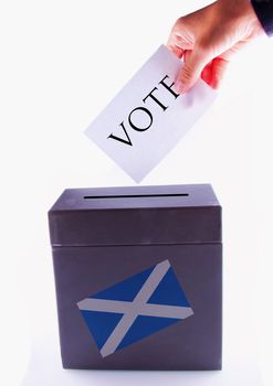 Urn for vote, with male hand posting vote and Scotland banner