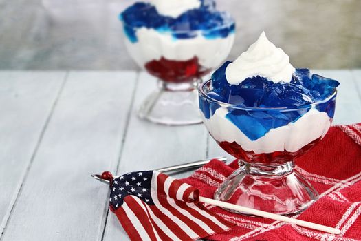 Gelatin layered dessert of cubes of red and blue jello with white fluffy whipped cream for the Fourth of July holiday. Shallow depth of field.