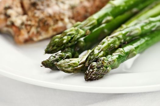 Freshly sauteed asparagus with salmon in background. Extreme shallow depth of field with selective focus on tip of asparagus.